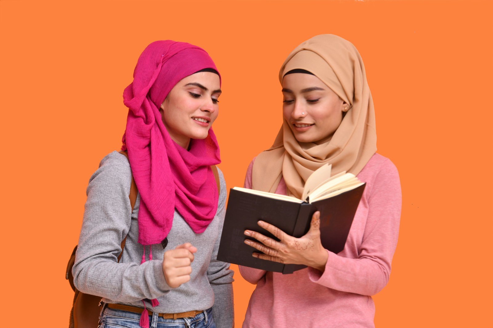 Two women in hijabs reading a book
