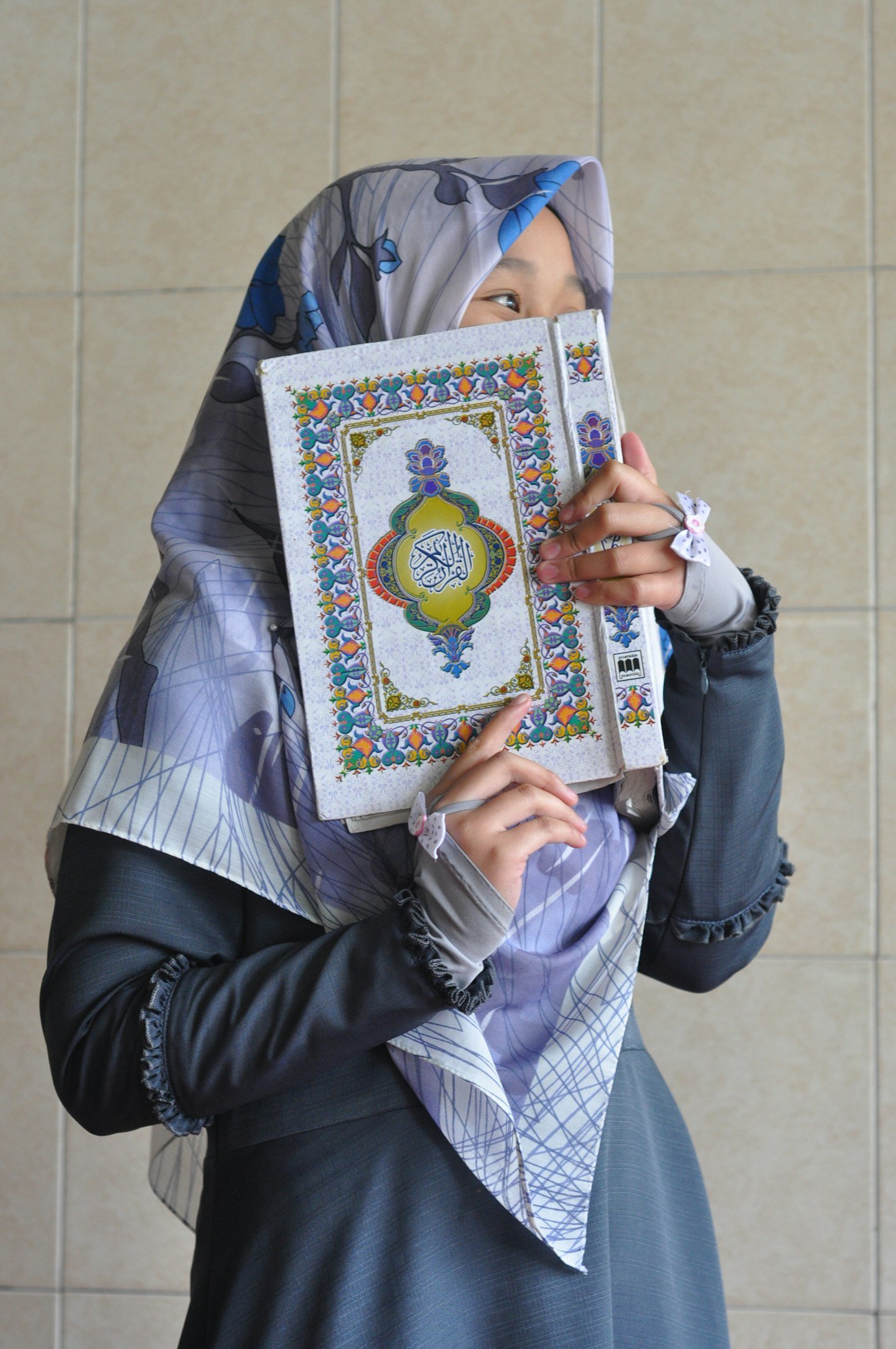 A woman in modest dress holding the Qur’an