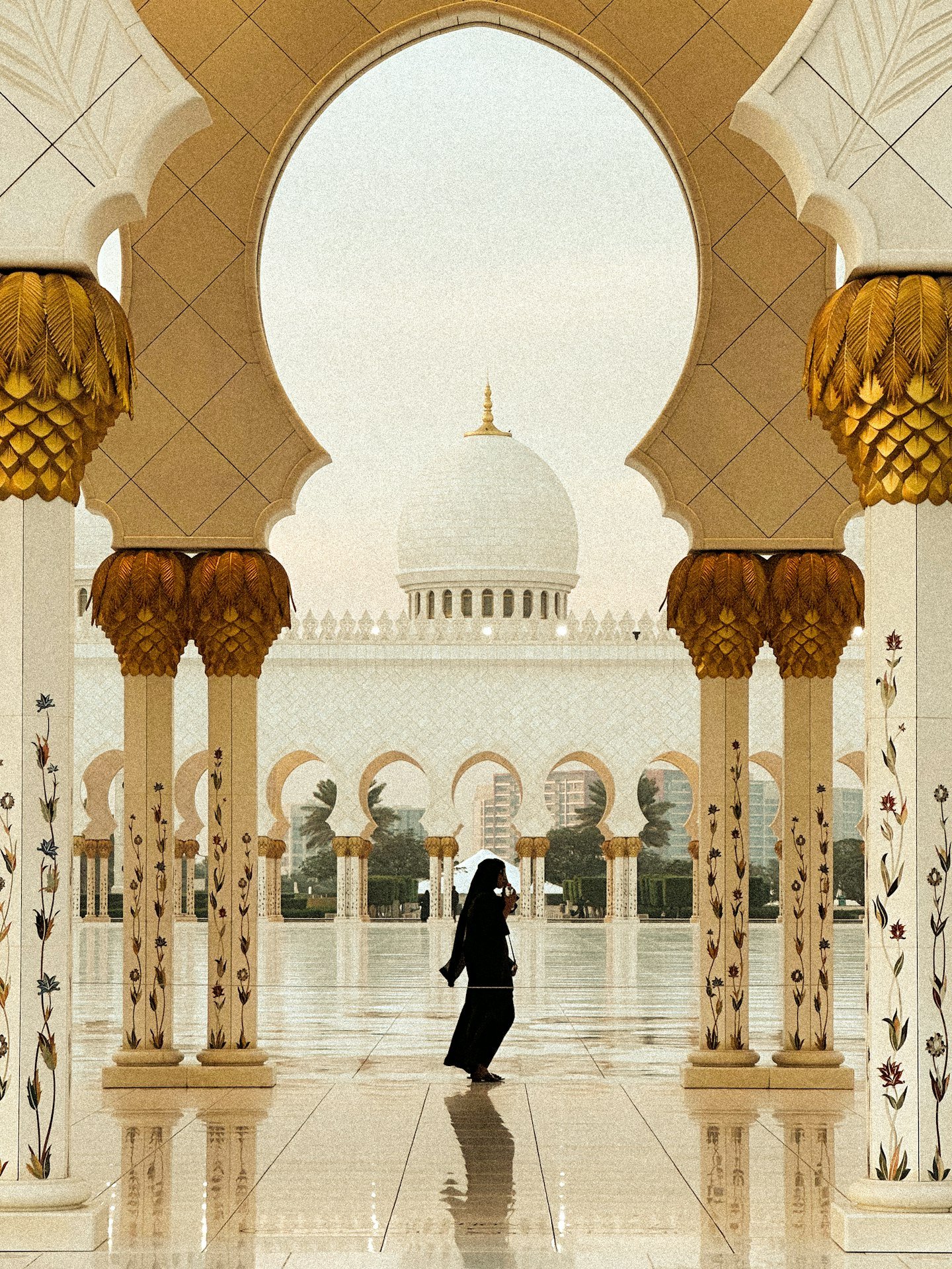 A woman in an abaya walking through a mosque courtyard